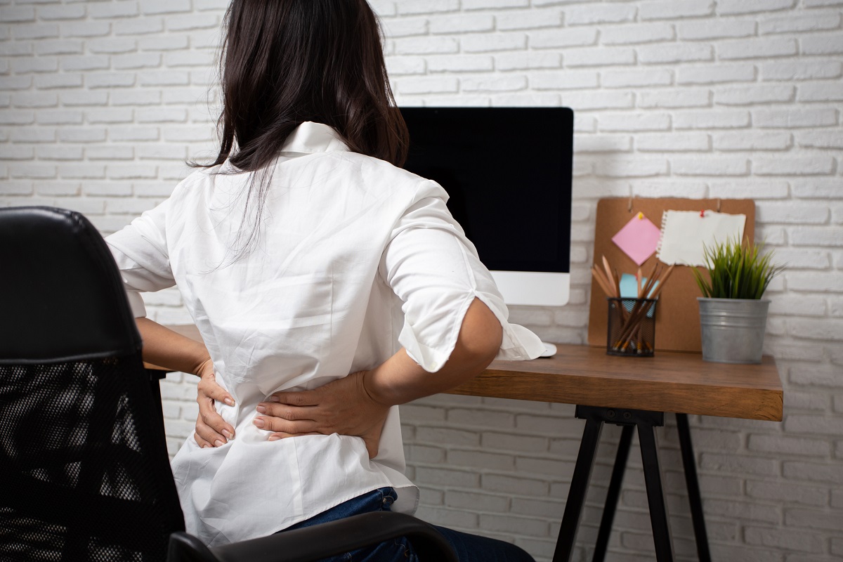 Frau im Home-Office mit Rückenschmerzen.