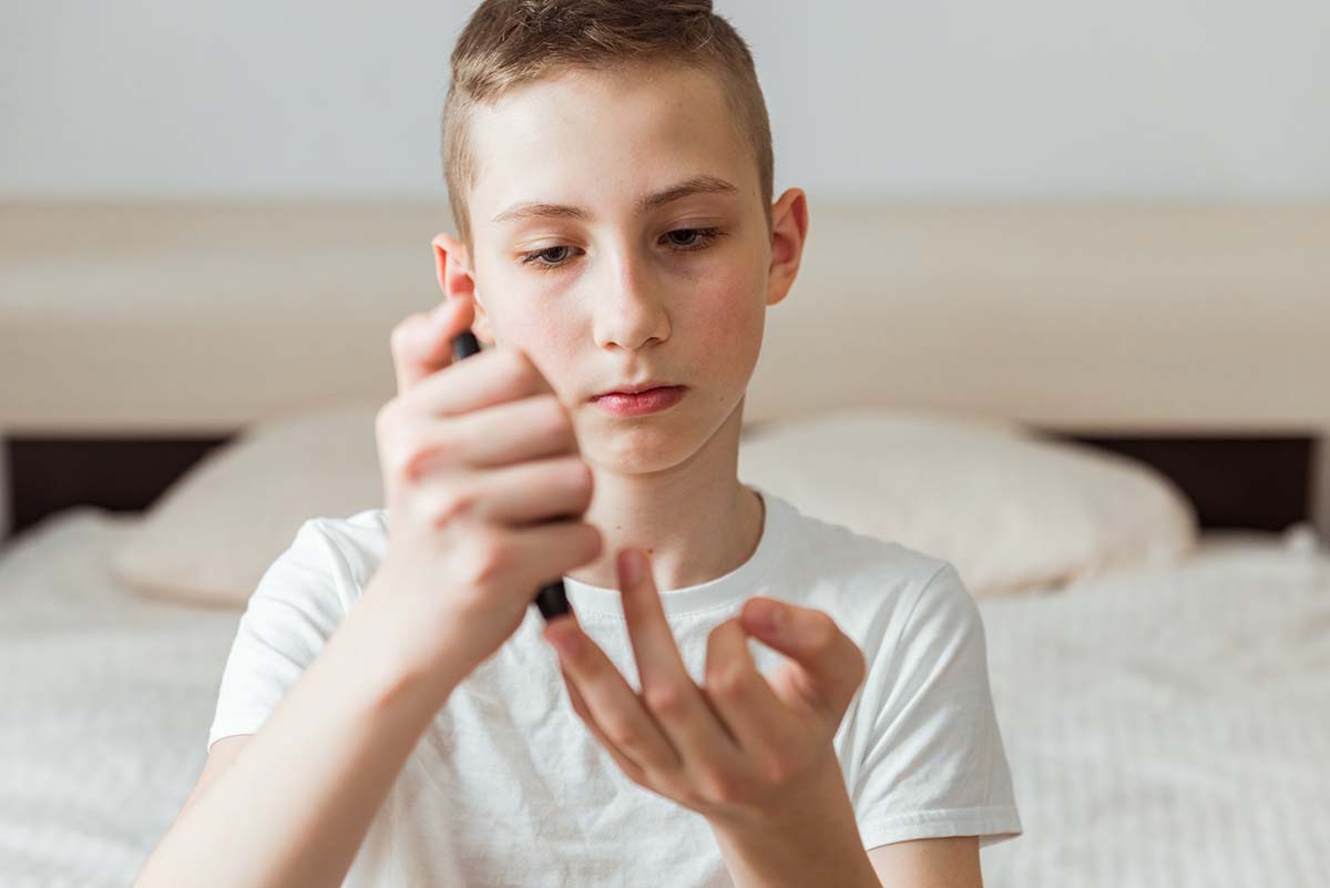Junge testet Blutzuckerwert am Finger.